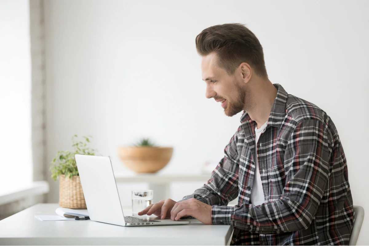 smiling-man-freelancer-working-laptop-communicating-online-using-software 1