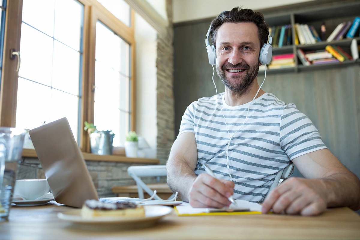 smiling-man-with-headphones-writing-his-diary-coffee-shop 1 (1)